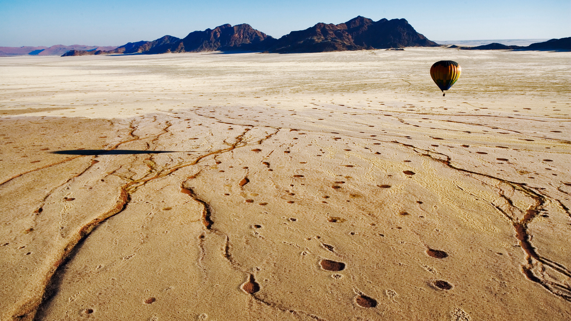 Aerial view of a hot air balloon over Namib desert. The circular “fairy circles” are derived from any vegetation & surrounded by tall grass.