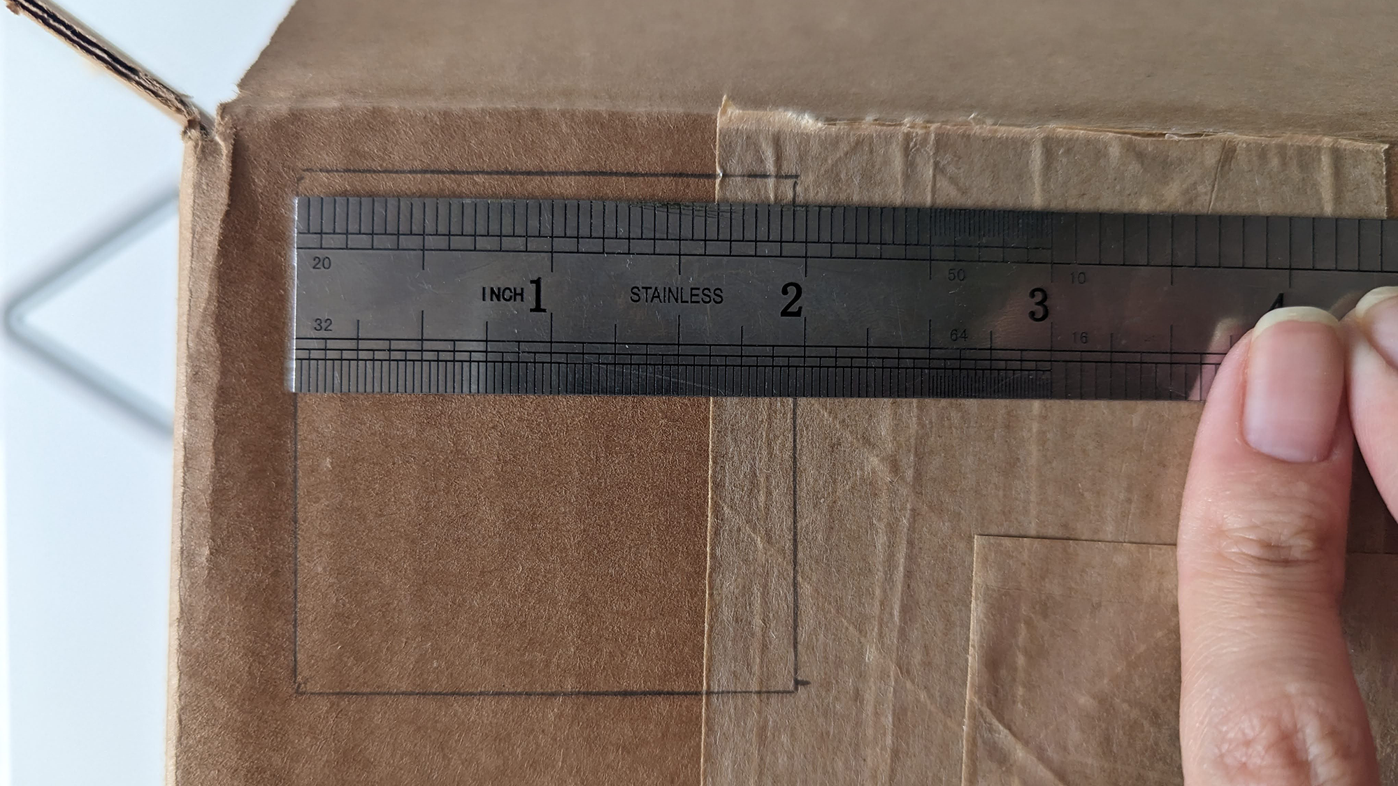 Ruler measuring a square on a cardboard box.