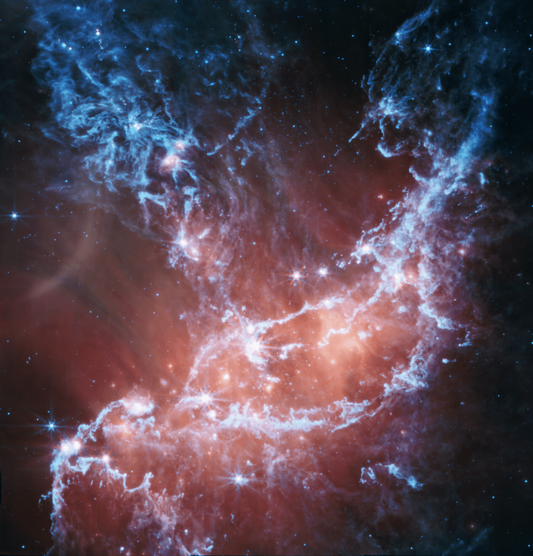 This new infrared image of NGC 346 from NASA’s James Webb Space Telescope’s Mid-Infrared Instrument (MIRI) traces emission from cool gas and dust. In this image blue represents silicates and sooty chemical molecules known as polycyclic aromatic hydrocarbons, or PAHs. More diffuse red emission shines from warm dust heated by the brightest and most massive stars in the heart of the region. Bright patches and filaments mark areas with abundant numbers of protostars.
