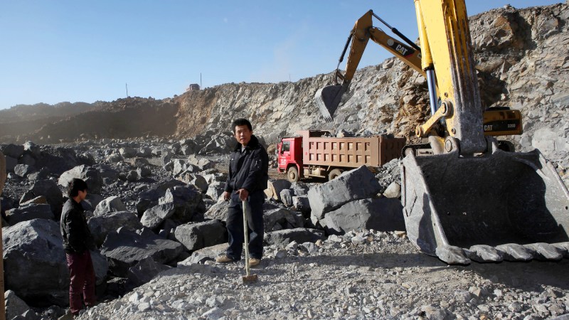 Workers at rare earth mineral mine next to equipment in China