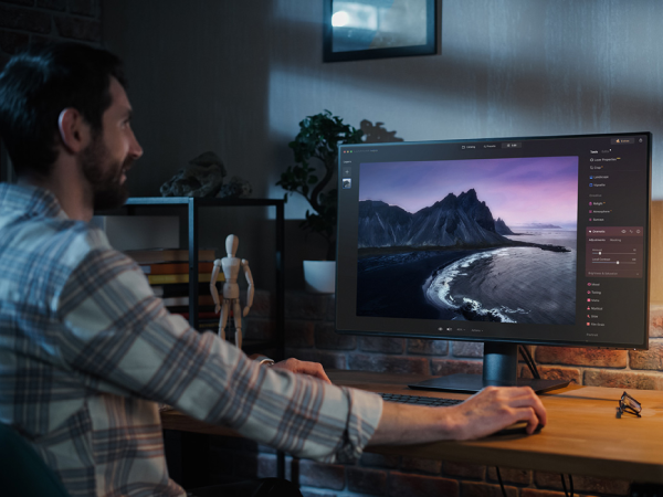 A person sitting at their desk using the Luminar Neo photo editor