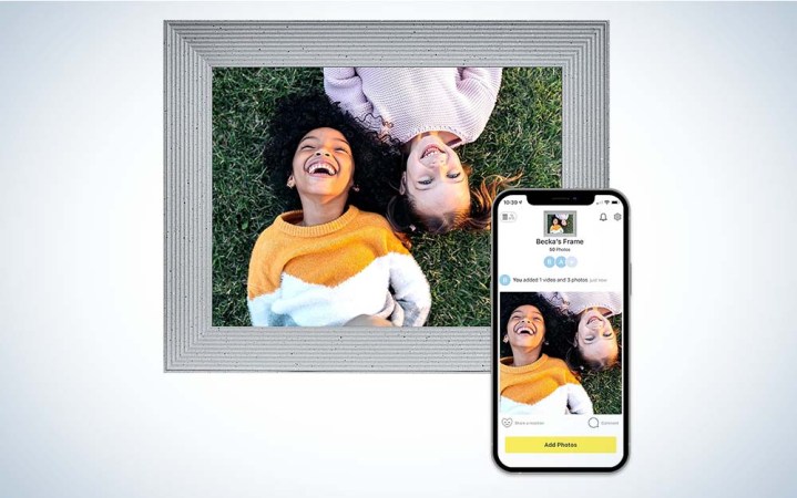  A picture of two little kids laughing in a gray picture frame next to an iPhone with the same image of the kids. 