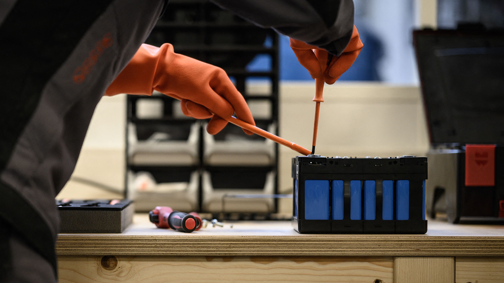 A mechanic works on a battery module of an electric car