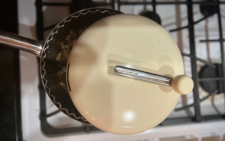  A cream Popsmith stovetop popper cooking on a white stove.