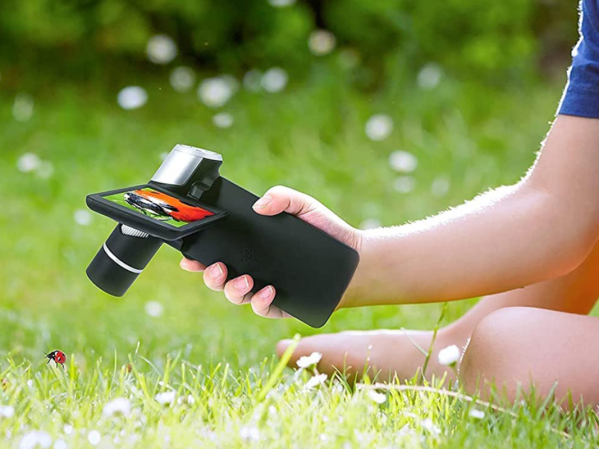 A person holding an LCD microscope in a backyard