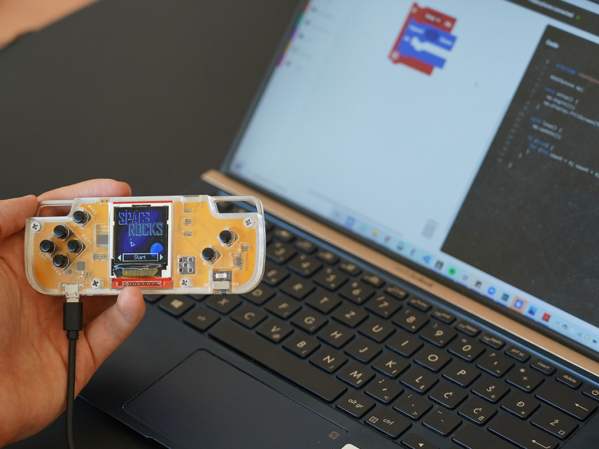 A person holding a yellow Nibble retro game console.