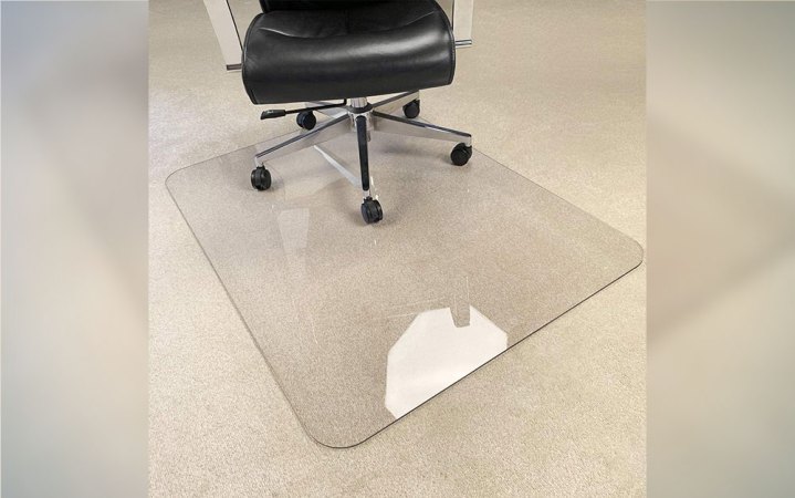  A MuArts alternative Chair Mat on a tan carpet with a desk chair on top.