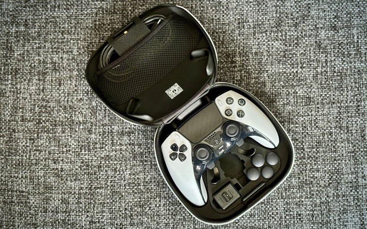  White and black PS5 DualSense Edge controller in its clamshell case on grey upholstery