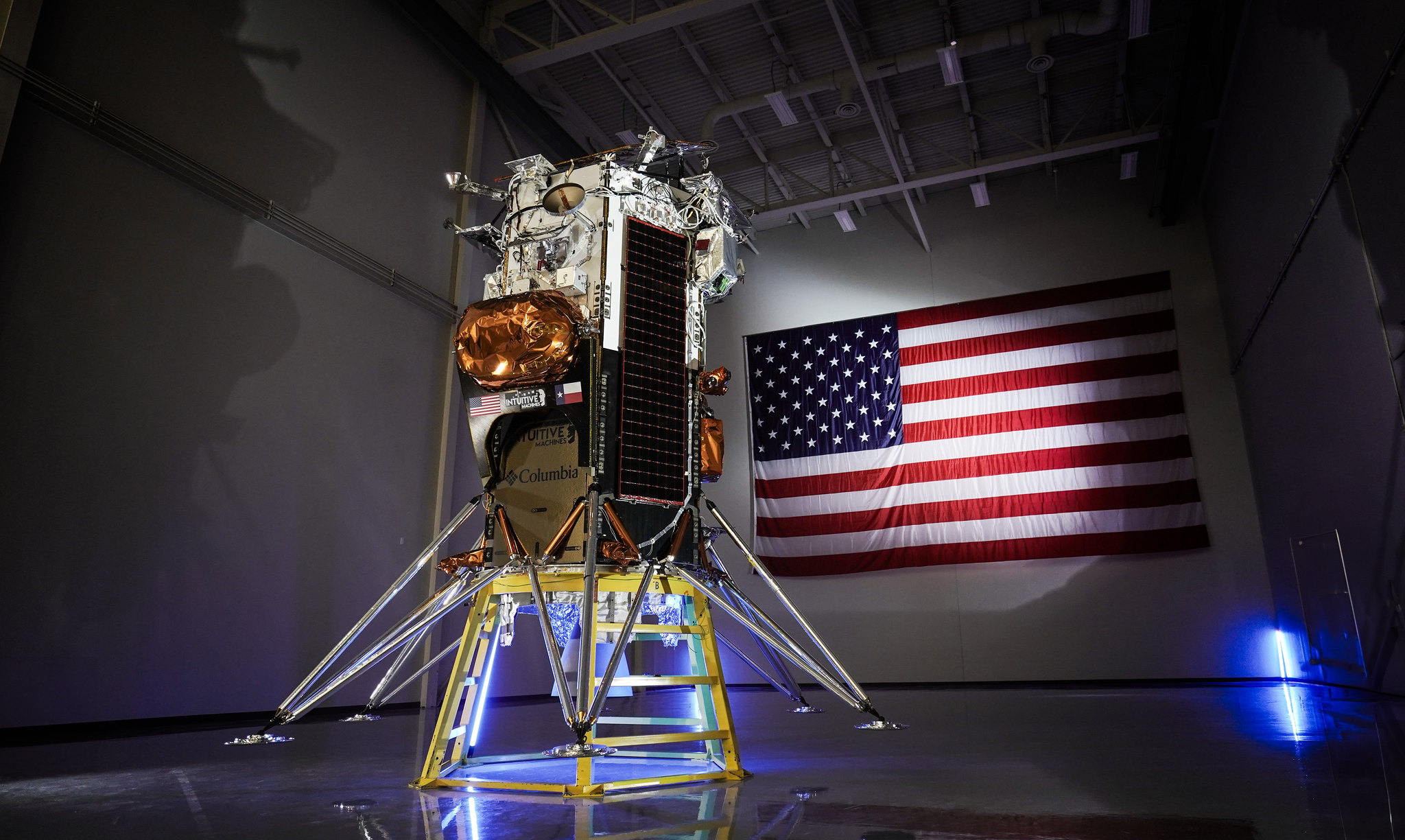 Intuitive Machines’ Nova-C moon lander stands upright on six legs next to an American flag.