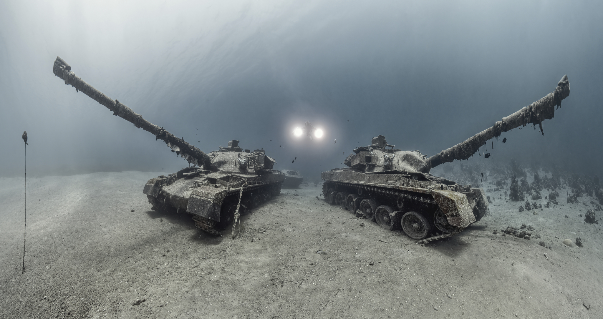 a diver swims between two tanks on the sea floor