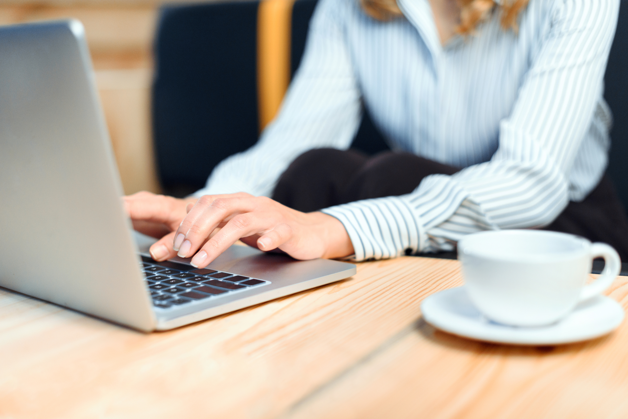 hands working on a laptop with a coffee