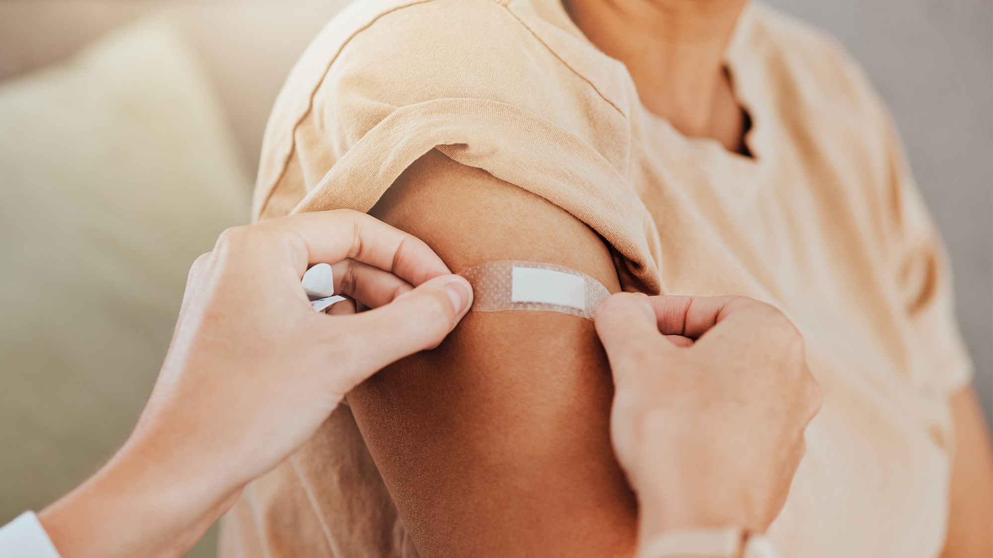 A doctor puts a bandage on the upper arm of a senior citizen.