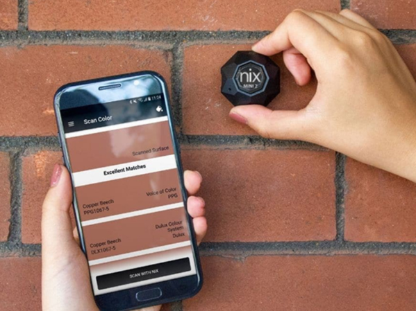 A person looking up the color of brick using a portable color sensor.