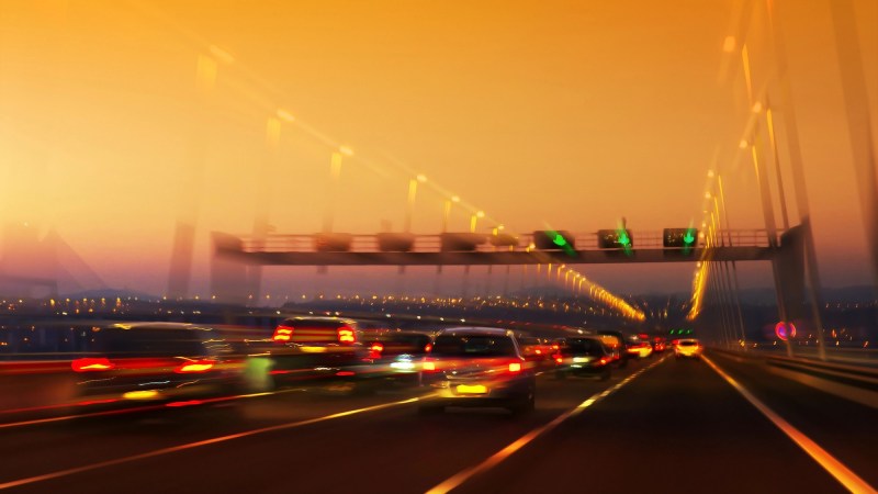 High traffic road with signs and light trails on sunset