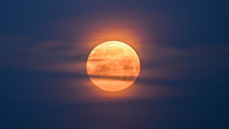 a full moon with some clouds obscuring it