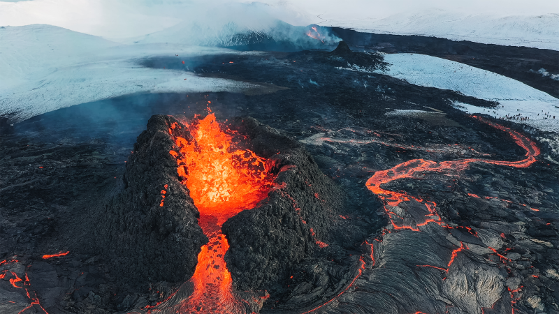 a volcano spews firey lava over molten rock and snow