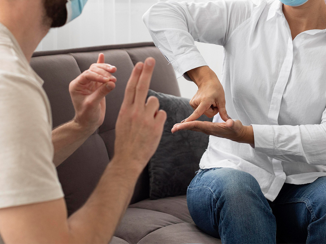 Two people using American Sign Language to communicate with each other.