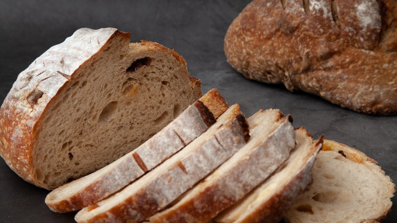 Sliced sourdough bread on dark cement background.