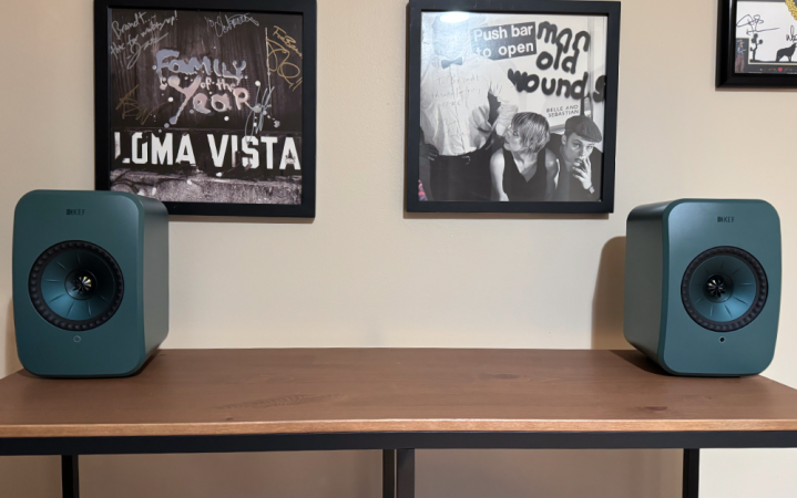  KEF LSX II LT on top of a table beneath framed vinyl albums. 