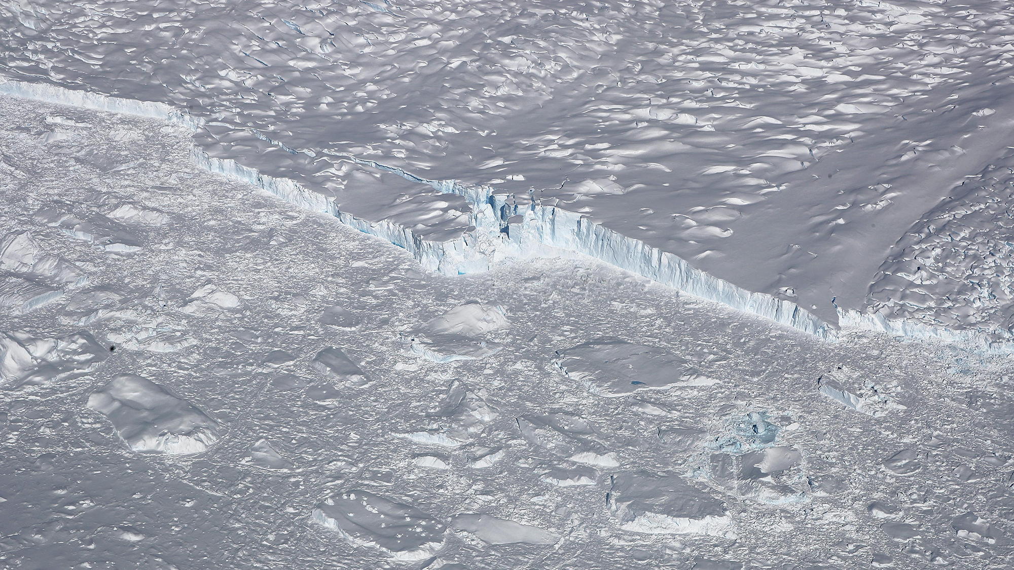 UNSPECIFIED, ANTARCTICA - OCTOBER 31: A calving glacier is seen from NASA's Operation IceBridge research aircraft, in the Antarctic Peninsula region, on October 31, 2017, above Antarctica. NASA's Operation IceBridge has been studying how polar ice has evolved over the past nine years and is currently flying a set of nine-hour research flights over West Antarctica to monitor ice loss aboard a retrofitted 1966 Lockheed P-3 aircraft. According to NASA, the current mission targets 'sea ice in the Bellingshausen and Weddell seas and glaciers in the Antarctic Peninsula and along the English and Bryan Coasts.' Researchers have used the IceBridge data to observe that the West Antarctic Ice Sheet may be in a state of irreversible decline directly contributing to rising sea levels. The National Climate Assessment, a study produced every 4 years by scientists from 13 federal agencies of the U.S. government, released a stark report November 2 stating that global temperature rise over the past 115 years has been primarily caused by 'human activities, especially emissions of greenhouse gases'. (Photo by Mario Tama/Getty Images)