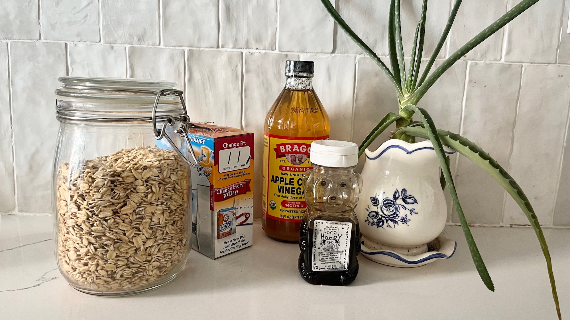 oats, baking soda, apple cider vinegar, honey, and aloe vera on a kitchen counter top