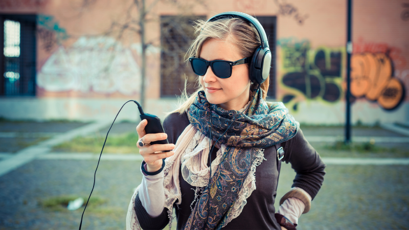 a woman listens to music with headphones on over hear ear