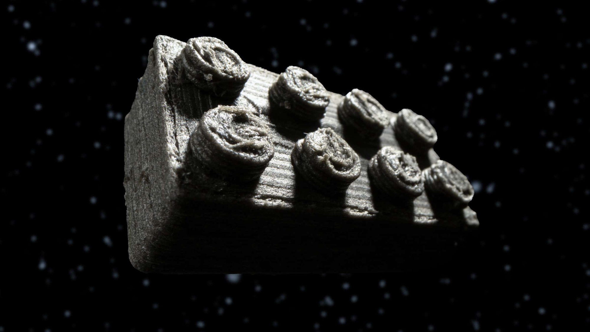 3D printed Lego moon brick made from meteorite dust against space background