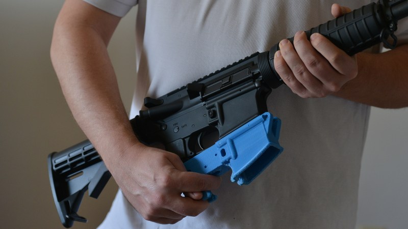 Travis Lerol holds an AR-15 assault rifle along with a rifle's lower receiver made of ABS (Acrylonitrile Butadiene Styrene) plastic that was constructed by his 3D printer at his home on Tuesday, February 12, 2012, in Glen Burnie, MD.