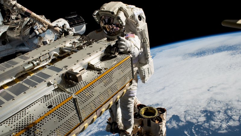 NASA astronaut and Expedition 68 Flight Engineer Woody Hoburg rides the Canadarm2 robotic arm while maneuvering a roll-out solar array toward the International Space Station's truss structure 257 miles above the Pacific Ocean. In the rear, is the SpaceX Dragon crew vehicle that docked to the Harmony module's forward port on March 3 carrying four SpaceX Crew-6 crew members.