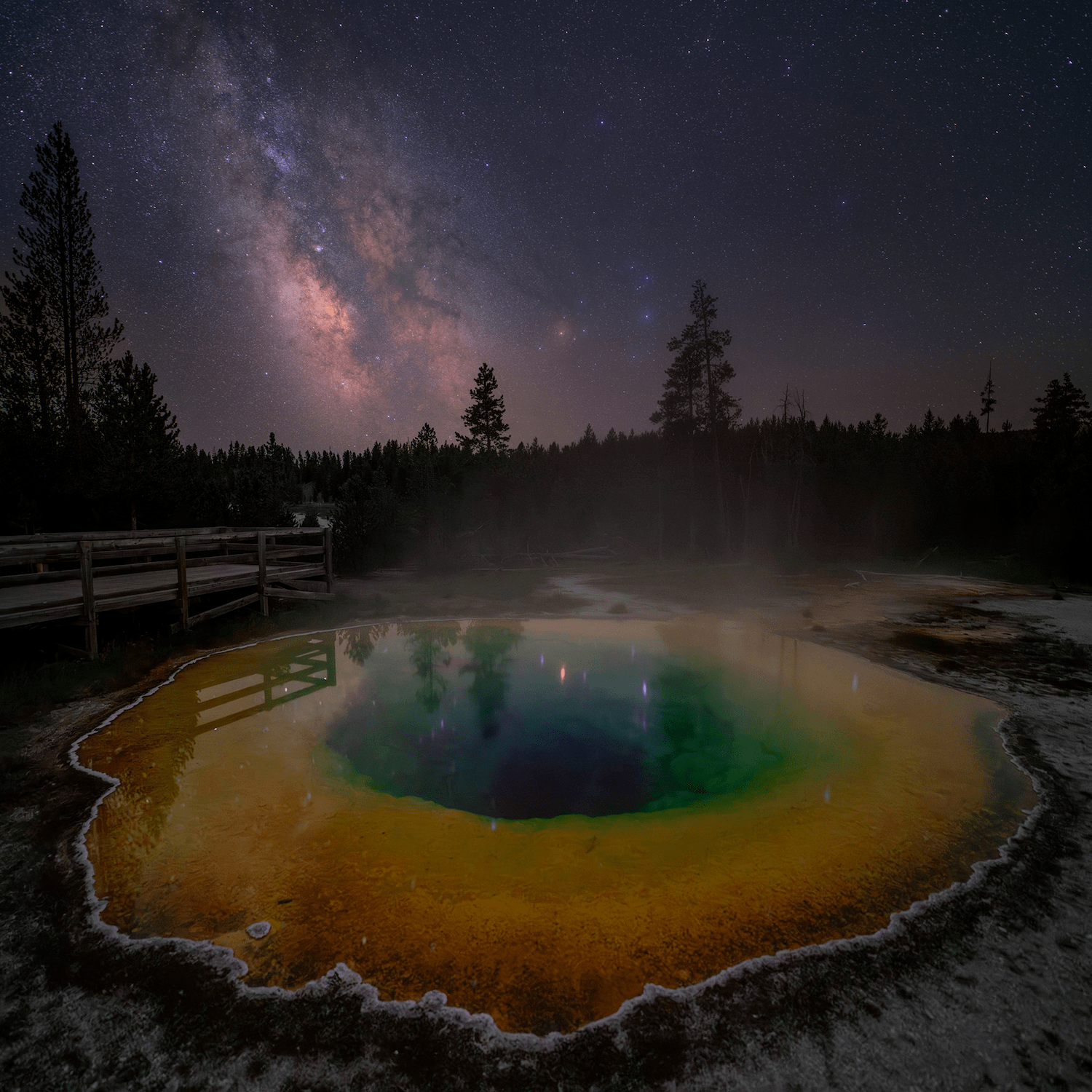a geothermal pool in the foreground with the milky way above