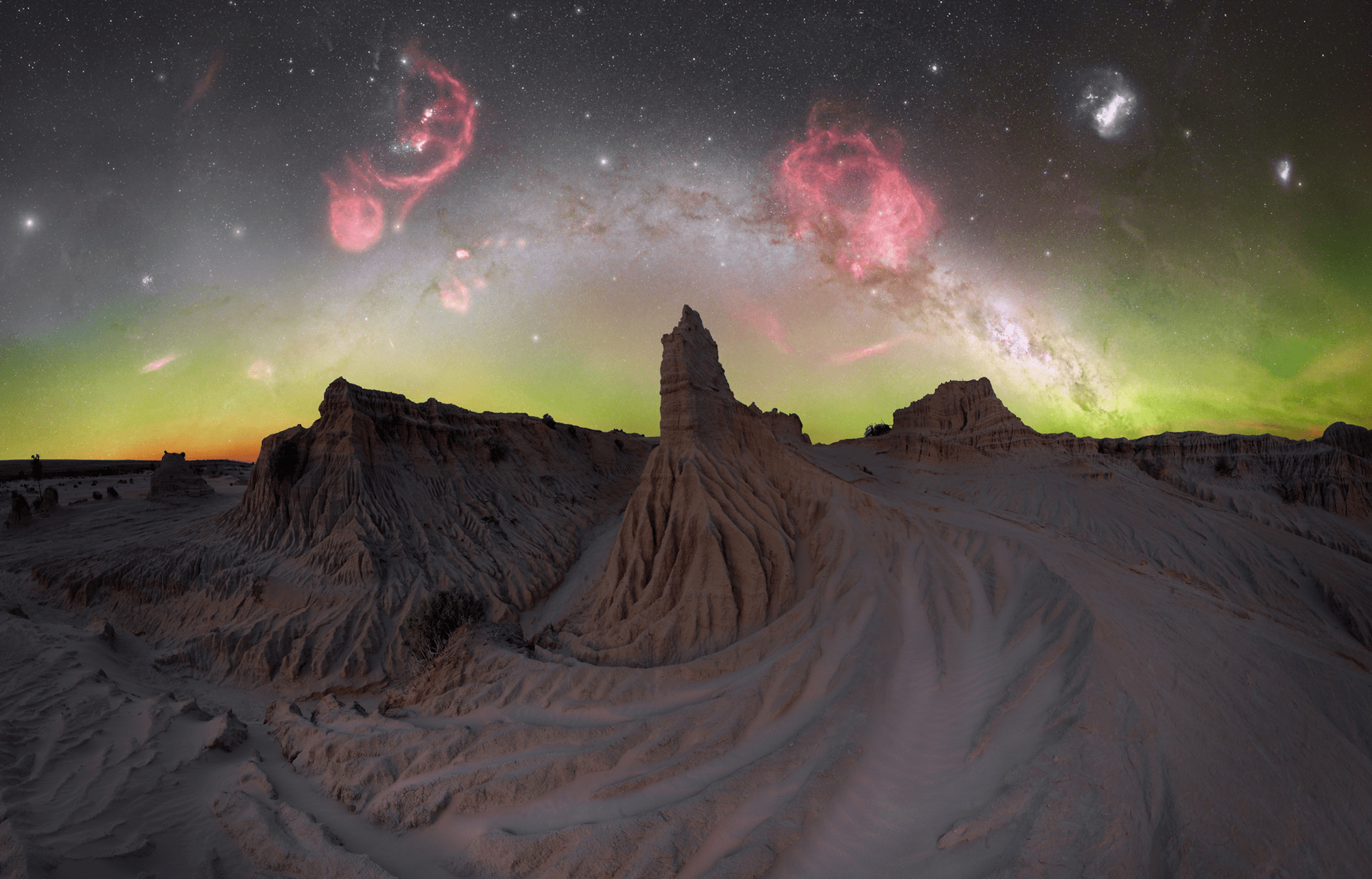 large red swirls and a green horizon over rock formations
