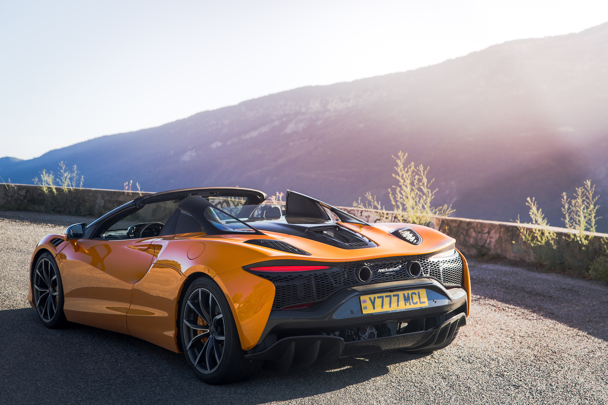 a sports car with the top down parked on the side of a rural road