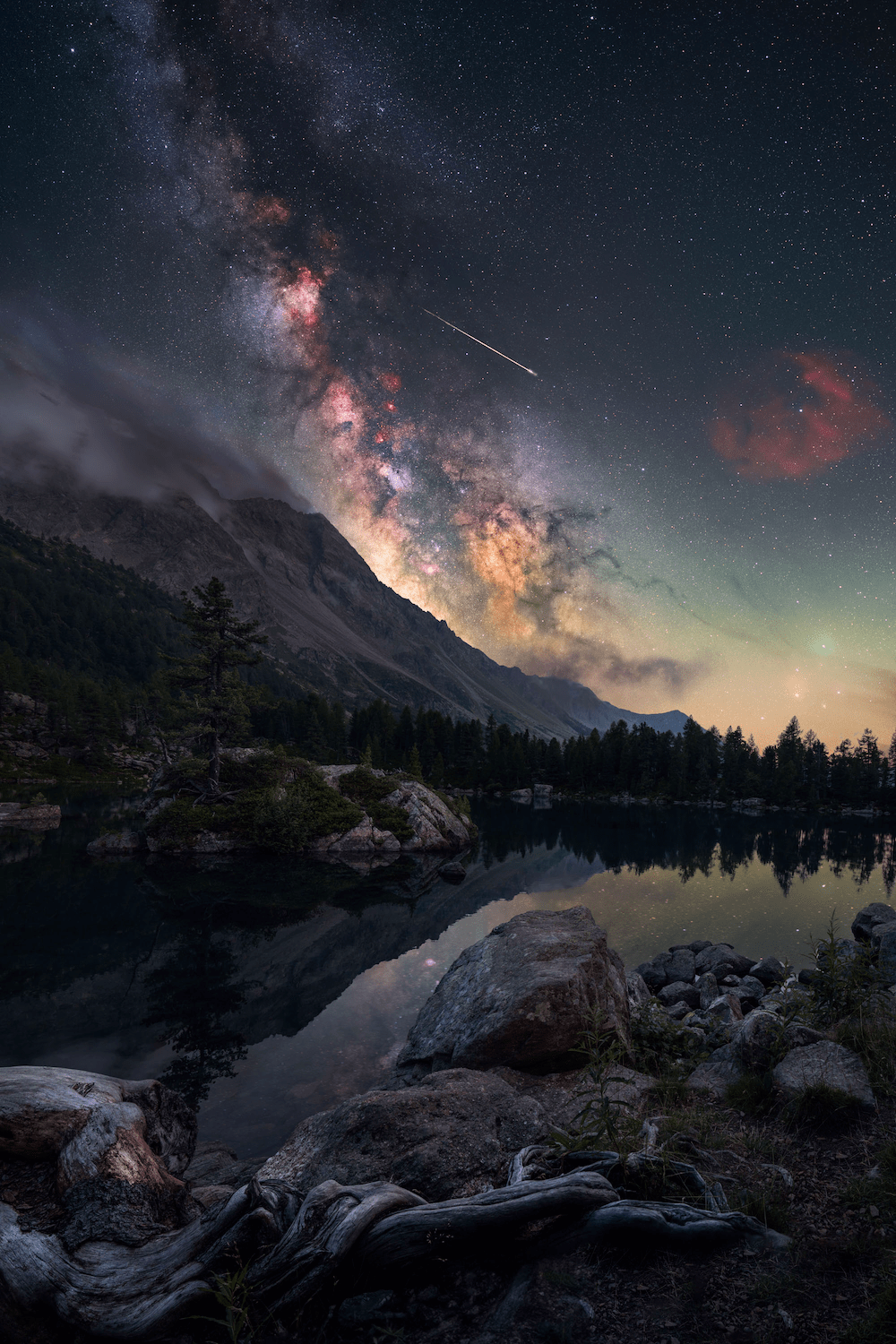 a mountain and lake scene with a shooting star and the milky way