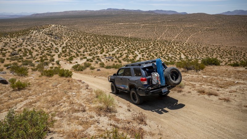 an off roading SUV drives through dirt and scrub