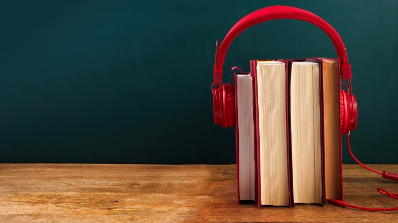 audio book concept with stack of books and headphones