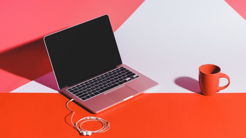 a pink laptop on a pink, red, white background with coffee cup