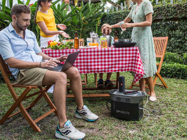 People sitting around a picnic table while a solar generator sits on the ground.