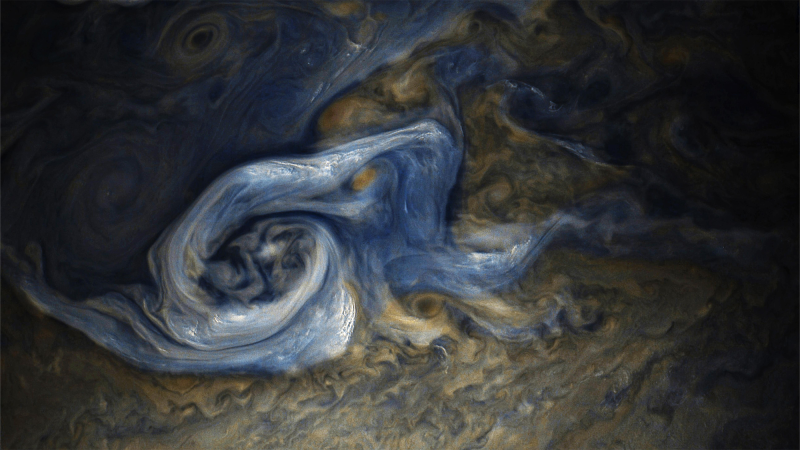 blue swirls swirling around white clouds and a brown surface on jupiter