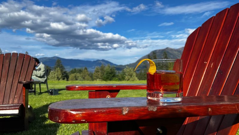 An NA Negroni sitting on the arm of an Adirondack chair with the Cascade Mountains in the background.
