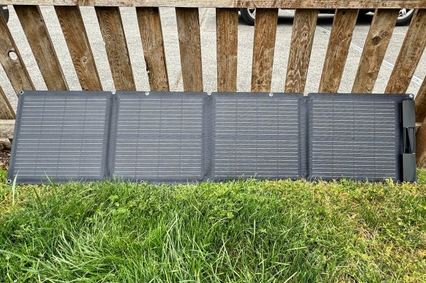 EcoFlow's 100W Solar Panel on grass by a fence.