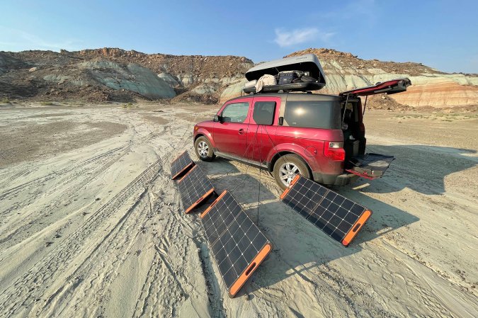  Jackery 100W Solar Panel by a car.