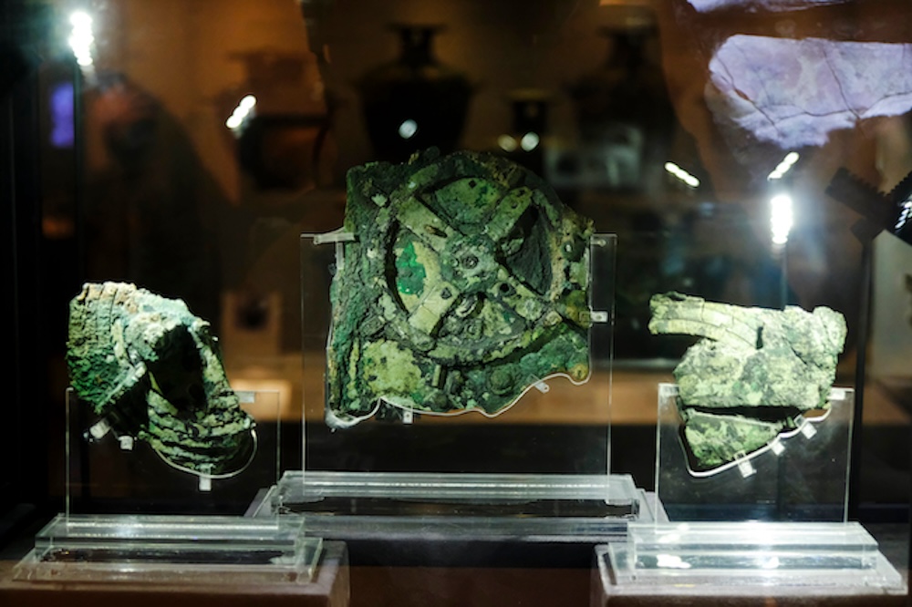 Visitors look at a fragment of the 2,100-year-old Antikythera Mechanism, believed to be the earliest surviving mechanical computing device, is seen at Museum in Athens, Greece on Aug. 26, 2018