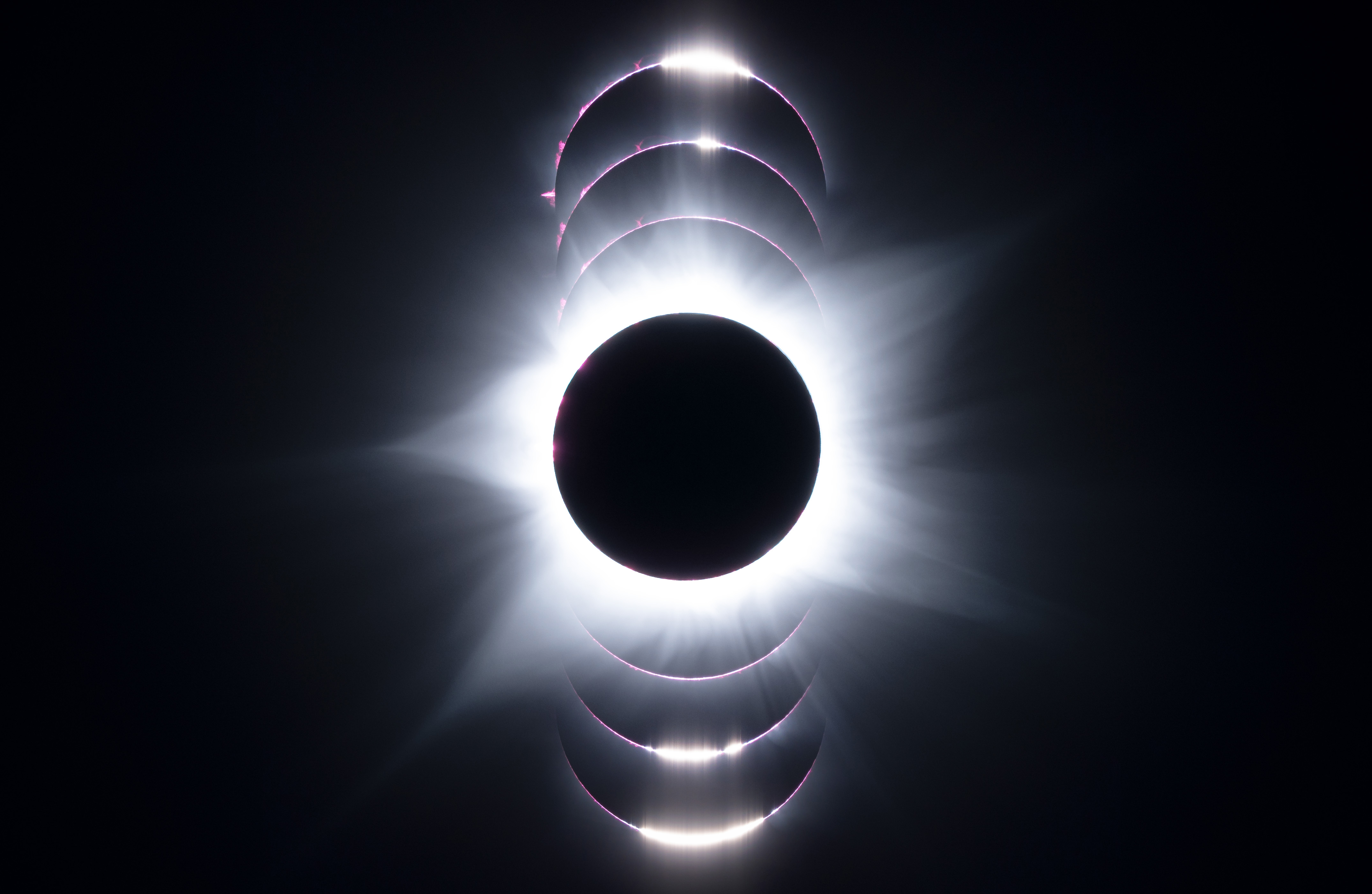 the stages of an eclipse showing the moon as a black dot and the pink colors of the sun behind it