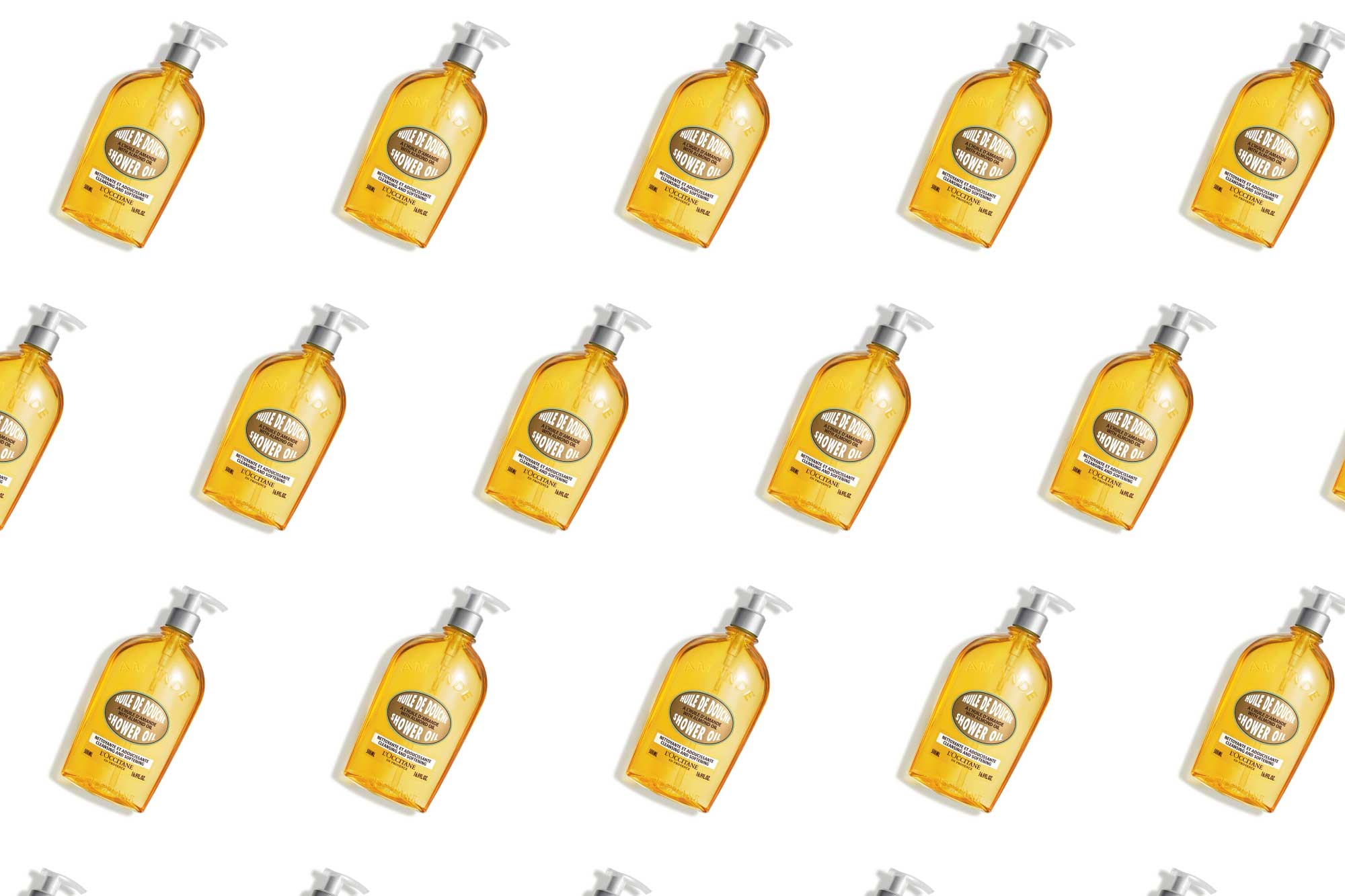 A bottle of L'Occitane almond shower oil in a pattern on a plain background