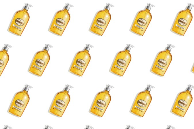 A bottle of L'Occitane almond shower oil in a pattern on a plain background