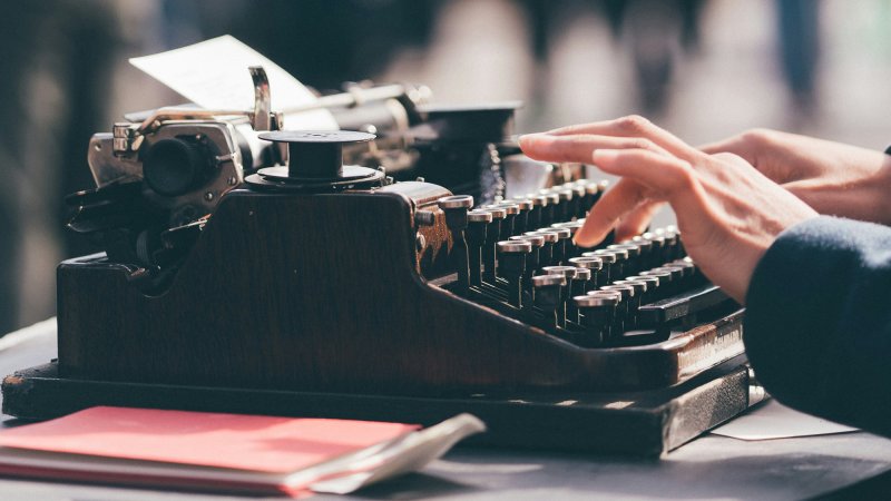 a person's hands typing on a typewriter