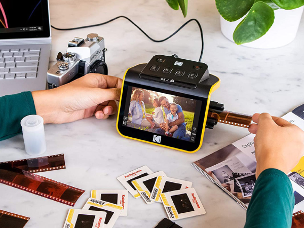 A person digitizing photos on a Kodak scanner.