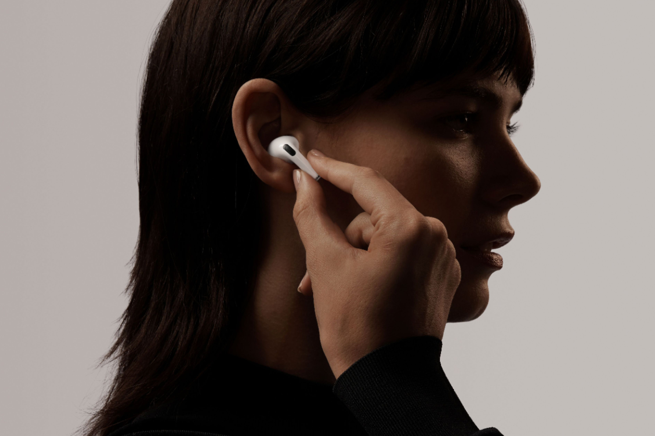 A person putting an AirPod in their ear.