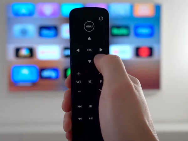 A person controlling a television using a simple universal AppleTV remote.