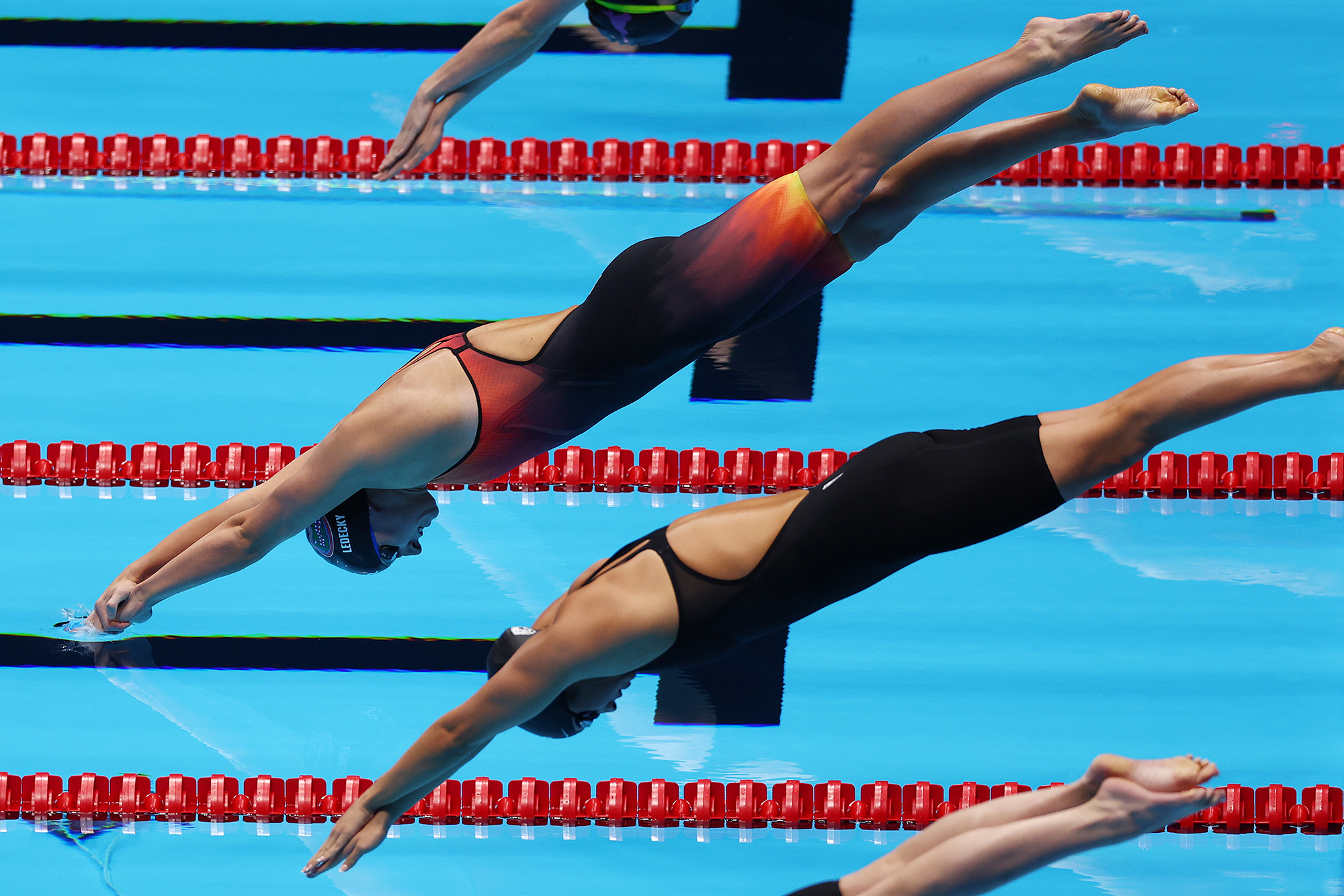 Katie Ledecky en drie andere zwemmers duiken het zwembad in